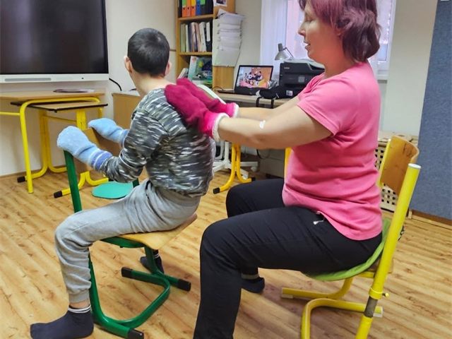 Rehabilitační cvičení žáka s pedagožkou na speciálních židlích